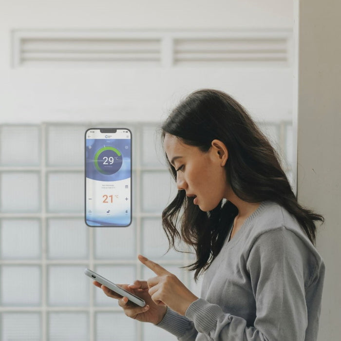 A woman is adjusting the temperature of her heat pump system using a thermostat app on her smartphone.