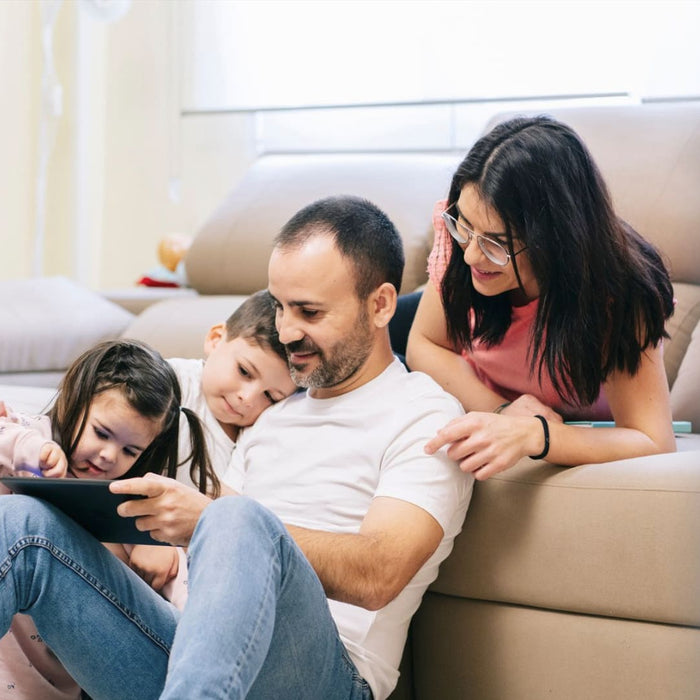 A family sitting on a couch looking for HVAC services on a tablet 